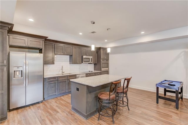 4240 Summer Breeze Way, Buford, GA 30518 - kitchen featuring appliances with stainless steel finishes, light wood-type flooring, a sink, a breakfast bar, and a kitchen island