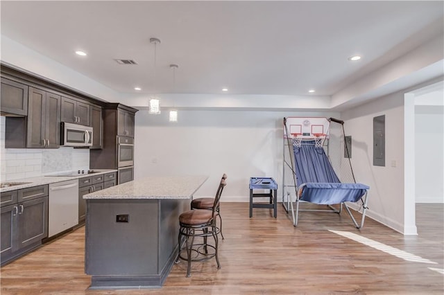 4240 Summer Breeze Way, Buford, GA 30518 - kitchen with appliances with stainless steel finishes, a center island, a breakfast bar area, dark brown cabinetry, and tasteful backsplash