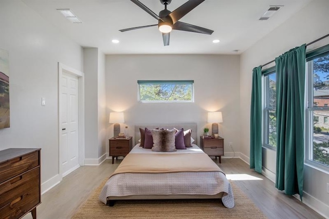 bedroom with ceiling fan, multiple windows, and light wood-type flooring