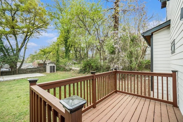 wooden terrace with a storage shed and a lawn