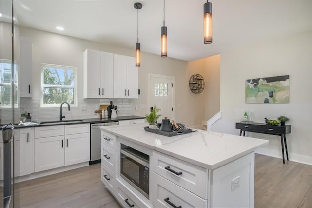 kitchen with sink, a center island, appliances with stainless steel finishes, pendant lighting, and white cabinets