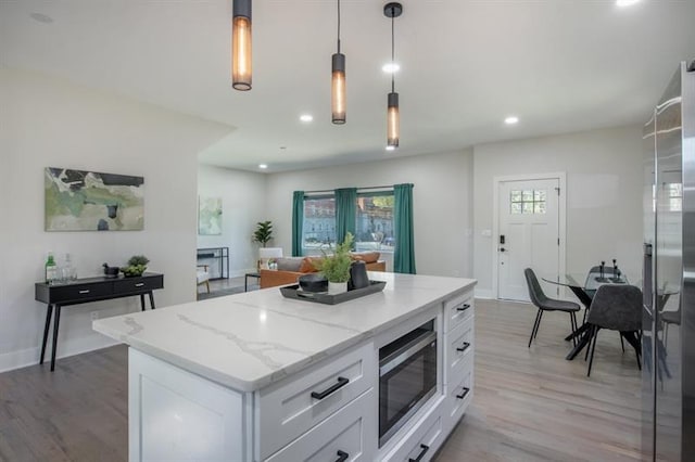 kitchen featuring a kitchen island, decorative light fixtures, white cabinets, stainless steel appliances, and light wood-type flooring