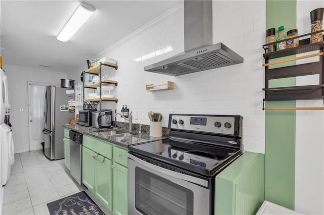 1452 Mercer Ave, Atlanta, GA 30337 - kitchen featuring appliances with stainless steel finishes, wall chimney exhaust hood, green cabinets, open shelves, and stacked washer and clothes dryer