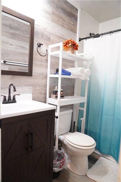 1452 Mercer Ave, Atlanta, GA 30337 - full bathroom featuring curtained shower, vanity, wood walls, and wood finished floors