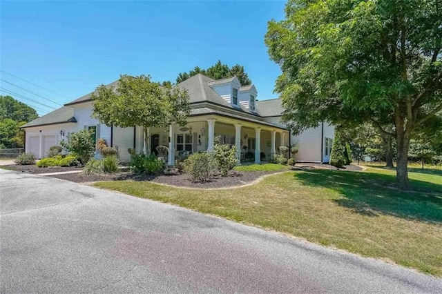 view of front of house with a garage, a front yard, and covered porch