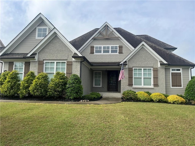 craftsman inspired home with a front yard, brick siding, and roof with shingles