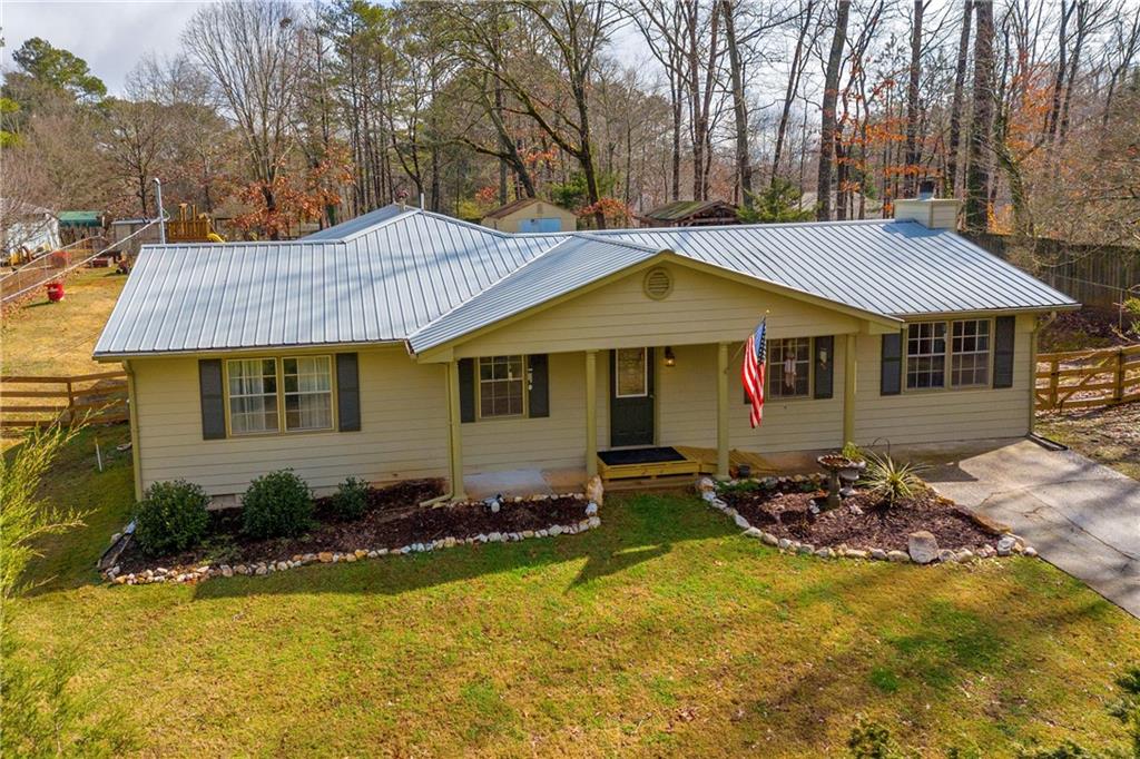 ranch-style house with metal roof, concrete driveway, a front yard, and fence