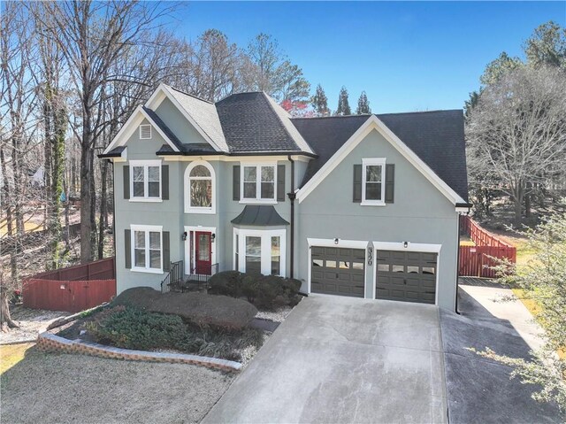 view of front of property with fence, concrete driveway, and roof with shingles