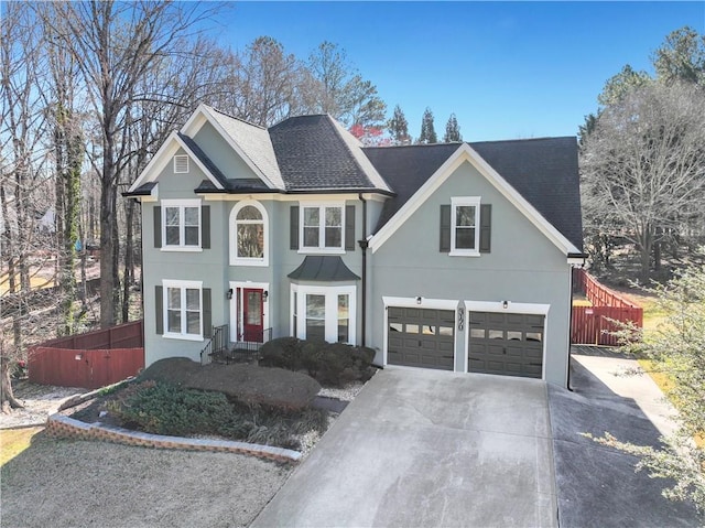 view of front of property with driveway, roof with shingles, fence, and stucco siding