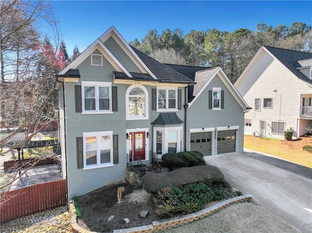 view of front facade featuring driveway, a shingled roof, fence, and stucco siding