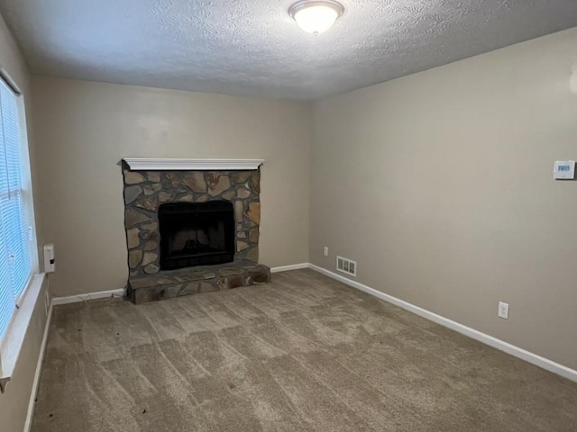 unfurnished living room featuring a stone fireplace, carpet, and a textured ceiling