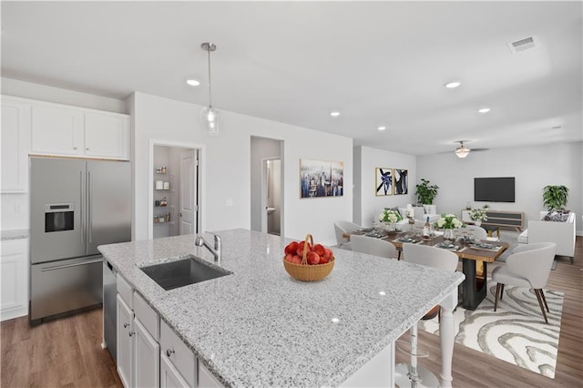 kitchen with hanging light fixtures, white cabinets, appliances with stainless steel finishes, and hardwood / wood-style floors