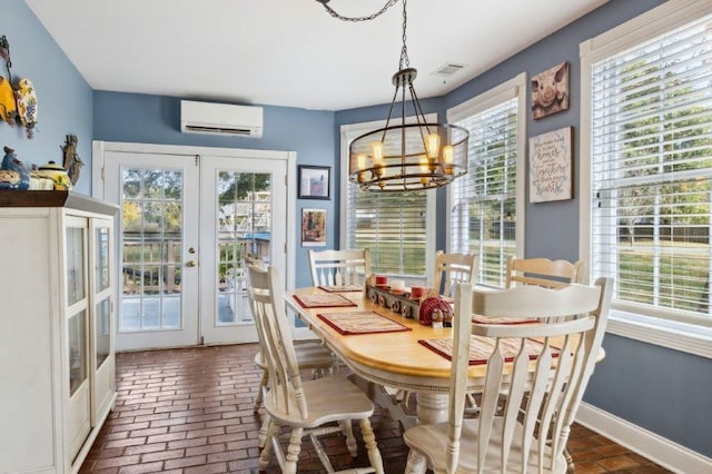 dining area with french doors, visible vents, a wall mounted AC, a chandelier, and brick floor
