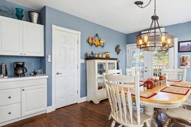 dining area with baseboards, a chandelier, and brick floor