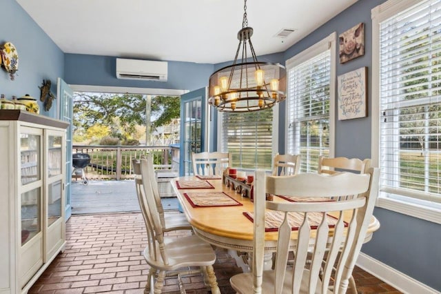 dining area with a healthy amount of sunlight, a wall unit AC, visible vents, a chandelier, and brick floor