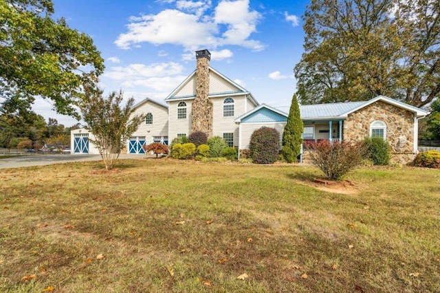 view of front of home with stone siding, driveway, a front yard, and a chimney