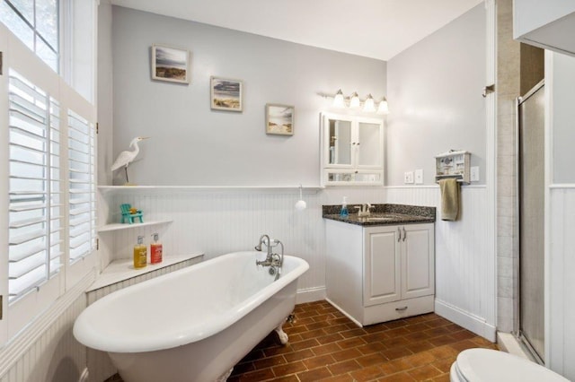 full bath featuring vanity, a stall shower, a freestanding tub, and a wainscoted wall