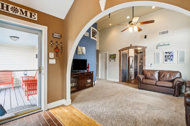 living area with arched walkways, ceiling fan, visible vents, and baseboards