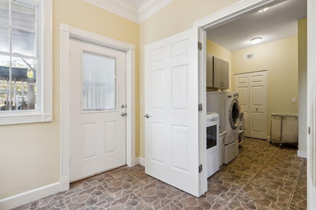 clothes washing area with independent washer and dryer, stone flooring, ornamental molding, and cabinet space