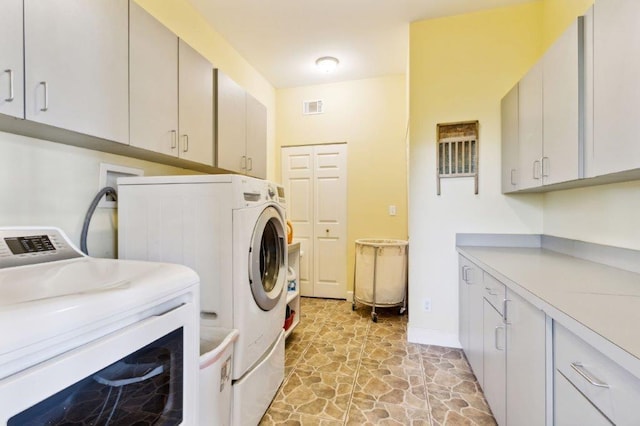 washroom featuring stone finish flooring, visible vents, cabinet space, baseboards, and separate washer and dryer