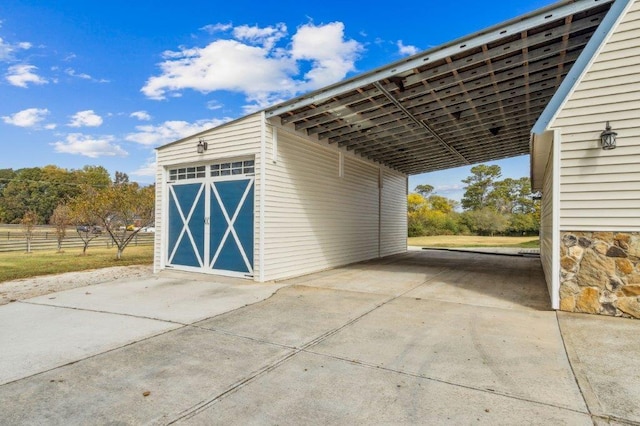 exterior space with concrete driveway, fence, an outbuilding, and a carport