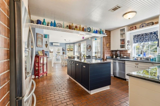 kitchen with dark countertops, brick floor, stainless steel appliances, and visible vents