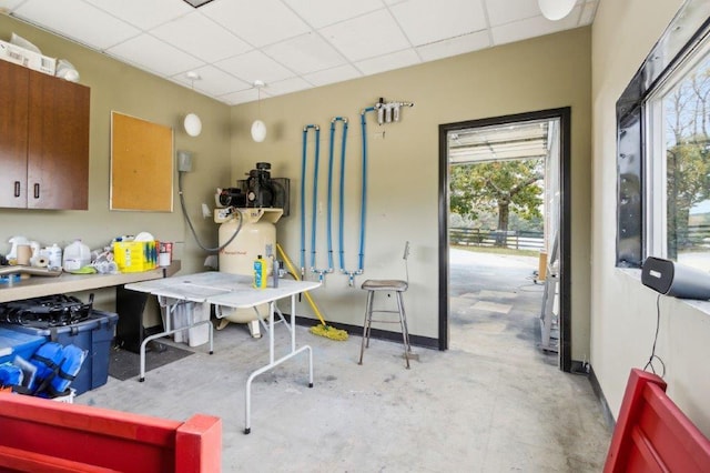 miscellaneous room featuring baseboards, concrete flooring, and a paneled ceiling
