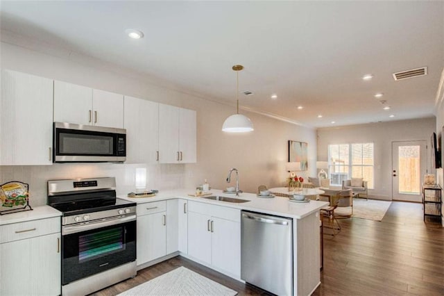 kitchen featuring sink, stainless steel appliances, kitchen peninsula, pendant lighting, and white cabinets