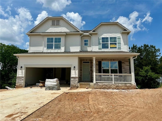 craftsman-style home with a garage, stone siding, covered porch, and driveway