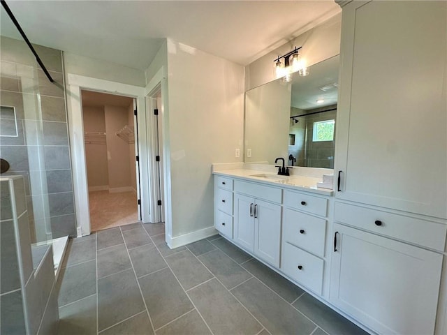 full bathroom featuring vanity, tile patterned flooring, baseboards, a spacious closet, and a stall shower