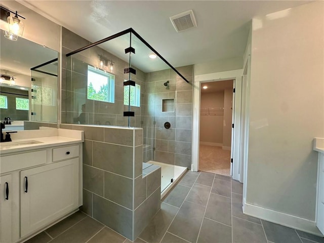 full bath with vanity, tile patterned floors, a shower stall, a spacious closet, and visible vents