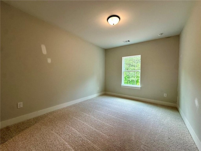 spare room with baseboards, light carpet, and visible vents