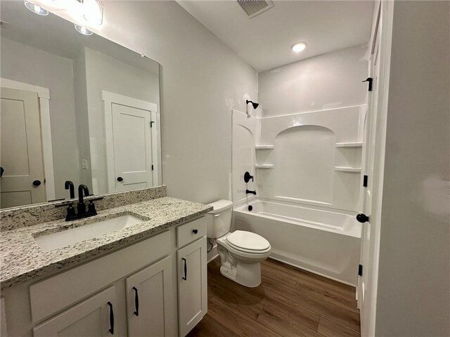 full bathroom with vanity, toilet, bathing tub / shower combination, wood finished floors, and visible vents