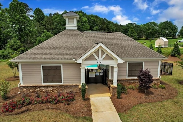 view of front of house featuring fence, a shingled roof, a front lawn, and brick siding