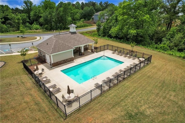 pool with a patio, an outdoor structure, fence, and a yard