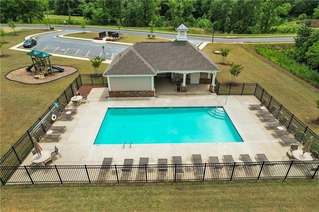 pool with fence, an outbuilding, a yard, and a patio area