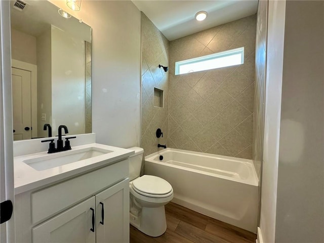 bathroom featuring visible vents, wood finished floors, vanity, toilet, and tub / shower combination
