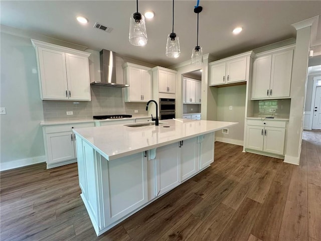 kitchen with visible vents, wall chimney exhaust hood, and white cabinets