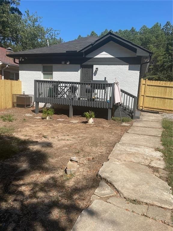 rear view of house featuring central AC unit and a wooden deck