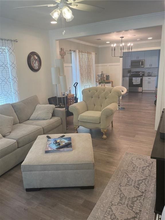 living room featuring dark hardwood / wood-style floors, plenty of natural light, crown molding, and ceiling fan with notable chandelier