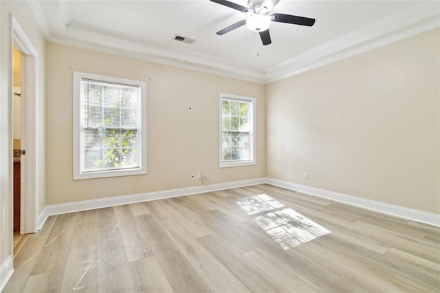 empty room featuring ornamental molding, a tray ceiling, light wood-type flooring, and ceiling fan