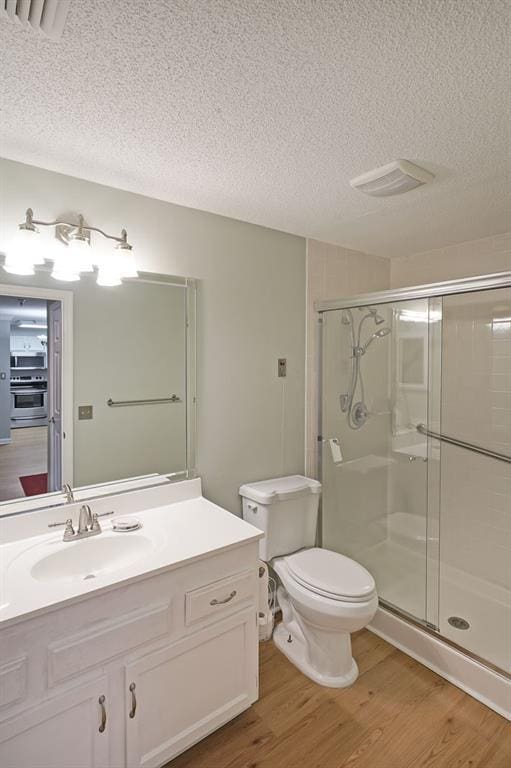 1800 Clairmont Lk Unit 313, Decatur, GA 30033 - bathroom featuring a textured ceiling, wood finished floors, a stall shower, toilet, and vanity
