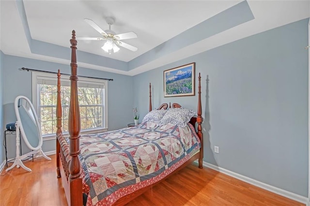 bedroom featuring a tray ceiling, ceiling fan, and hardwood / wood-style flooring