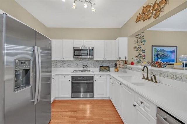 kitchen with white cabinetry, sink, tasteful backsplash, light hardwood / wood-style flooring, and appliances with stainless steel finishes