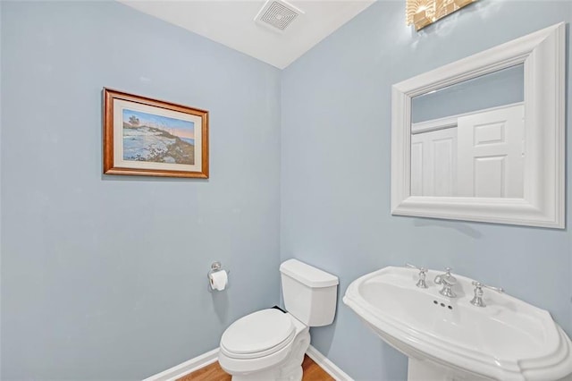 bathroom featuring wood-type flooring, toilet, and sink