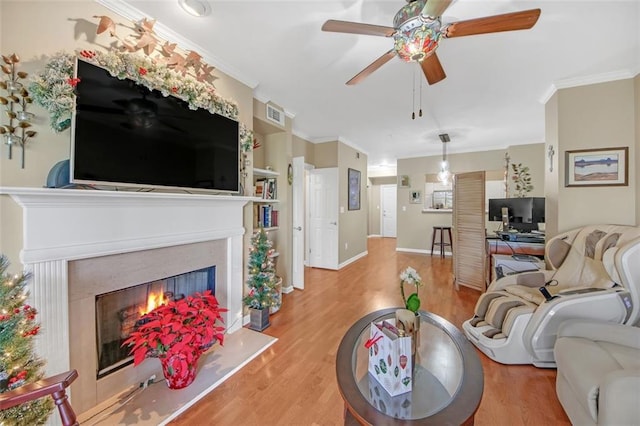 living room featuring light wood-type flooring, ceiling fan, and ornamental molding