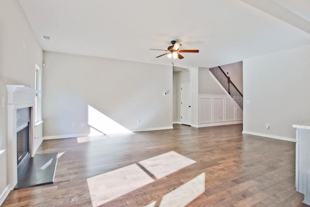 238 Linford Dr, Locust Grove, GA 30248 - unfurnished living room with a ceiling fan, wood finished floors, a glass covered fireplace, stairs, and baseboards
