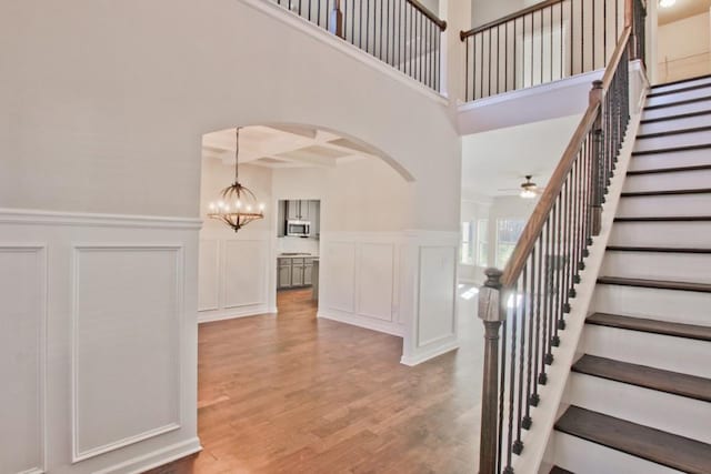 238 Linford Dr, Locust Grove, GA 30248 - stairway with a decorative wall, arched walkways, a chandelier, wood finished floors, and a ceiling fan
