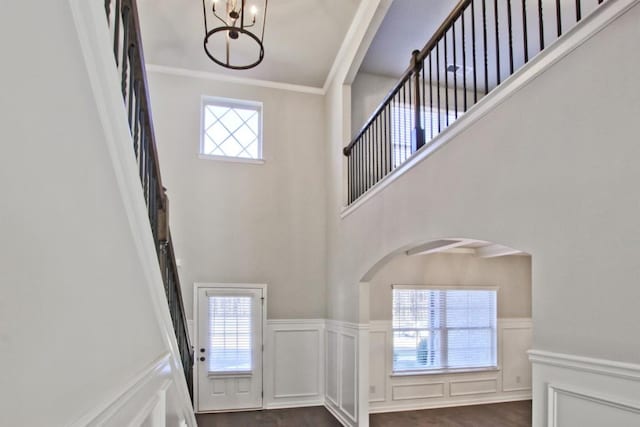 238 Linford Dr, Locust Grove, GA 30248 - entrance foyer with a decorative wall, a chandelier, arched walkways, ornamental molding, and a wainscoted wall