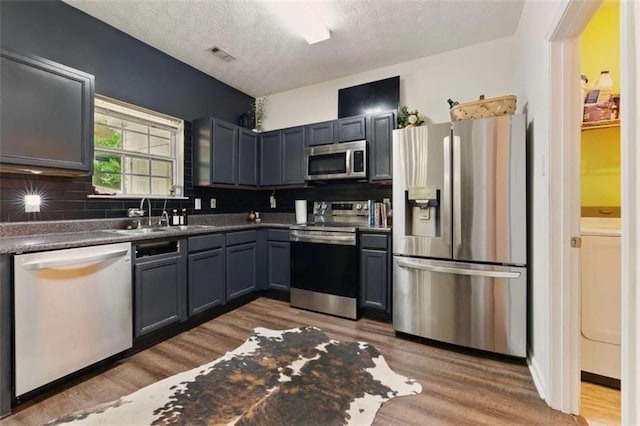 1689 Camden Forrest Way, Riverdale, GA 30296 - kitchen with appliances with stainless steel finishes, a sink, wood finished floors, decorative backsplash, and a textured ceiling